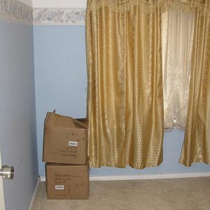 Yucky blue walls with wallpaper and horrid curtains